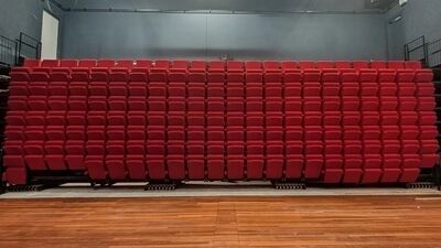 vooraanzicht van een ingeschoven tribune in de theaterzaal, het lijkt zo een muur van rode stoelen