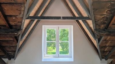 in de nok van het gebouw, houten balken en een doorkijkje door het raam op het nabijgelegen park